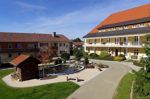 Innenhof mit kleinem Teich, Sitzbänken und zwei mehrstöckigen Gebäuden mit roten Dächern unter blauem Himmel
