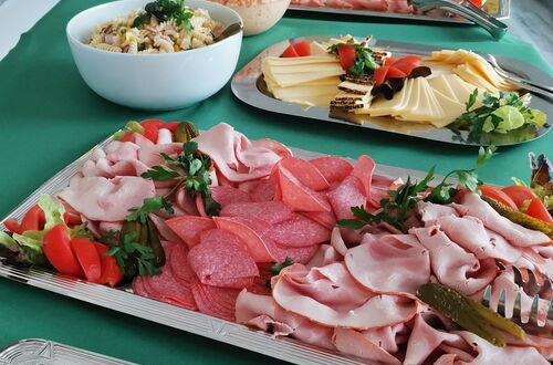 Buffet mit verschiedenen Aufschnittplatten, Käse, Salaten und Brötchen auf grün gedeckten Tischen