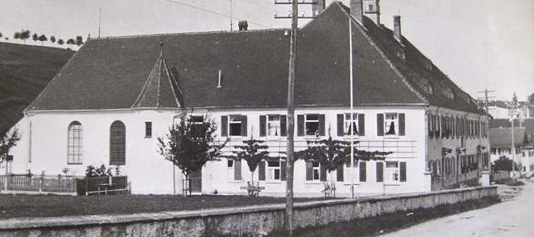 Großes historisches Gebäude mit Satteldach, mehreren Fenstern und einem kleinen Turm im Hintergrund