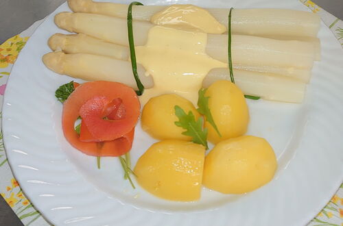 Weißer Spargel mit Sauce Hollandaise, drei Kartoffeln und einer Tomatenscheibe auf weißem Teller